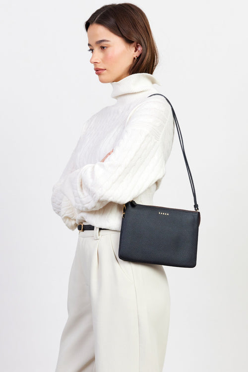 Woman carrying a black handbag on a white background