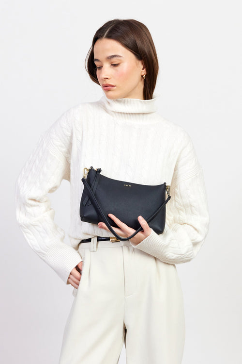 Woman holding a black handbag against a white background