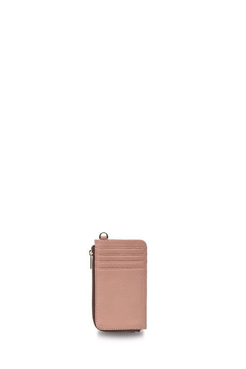 A slim, vertical blush pink leather card holder wallet with a zipper closure and a small metal ring detail on the top left, shown against a solid white background.