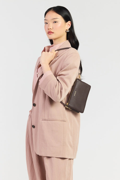 Woman wearing a pink suit with a matching handbag on a light gray background
