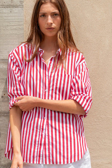 Woman wearing a red and white striped shirt against a beige wall.
