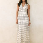 Woman wearing a long black and white patterned dress against a plain background