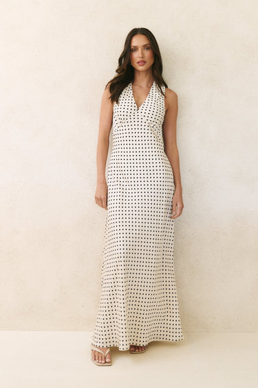 Woman wearing a long black and white patterned dress against a plain background