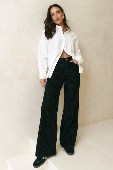 model wearing black animal print jeans and white shirt 