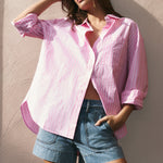 Woman wearing a pink shirt and denim shorts against a textured wall.
