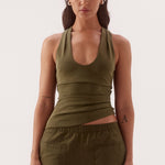 Woman wearing an olive green tank top and wide-leg pants on a white background