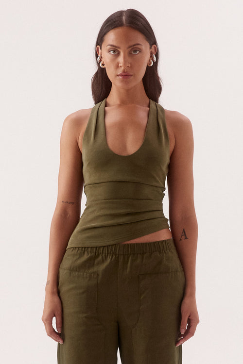 Woman wearing an olive green tank top and wide-leg pants on a white background