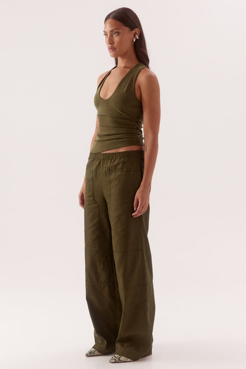 Woman wearing an olive green tank top and wide-leg pants on a white background