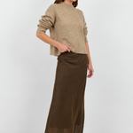 Woman wearing a beige sweater and brown skirt on a white background
