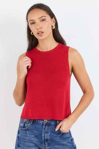 Woman wearing a red sleeveless top and blue jeans on a white background