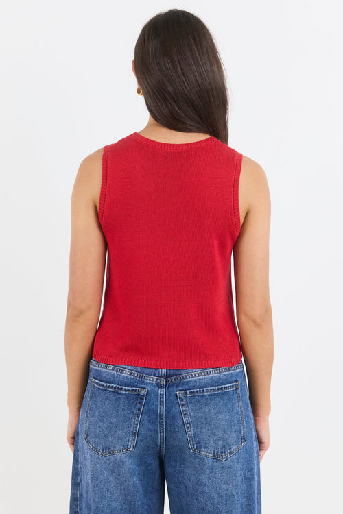 Person wearing a red sleeveless top and blue jeans on a white background