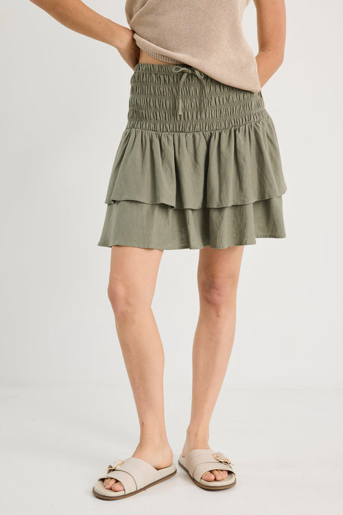 Person wearing a green layered skirt on a white background
