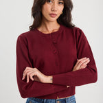 Woman wearing a burgundy sweater and blue jeans against a white background