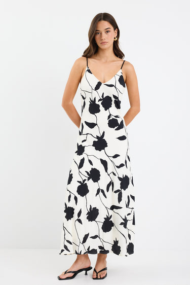 A strappy ivory dress with a bold black floral print, featuring a bias-cut design and fully lined interior. Made from 80% Viscose and 20% Nylon for a soft, breathable feel.