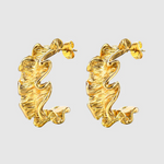A pair of gold-toned hoop earrings with a unique ruffled design, featuring a textured, wavy surface that mimics soft fabric folds for a sculptural, organic look.