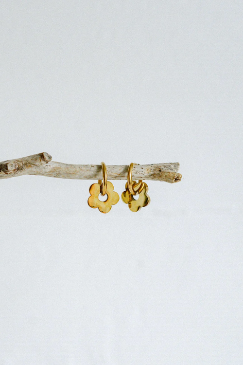 A pair of gold-toned hoop earrings featuring dangling flower-shaped charms with smooth, rounded petals and a high-shine finish