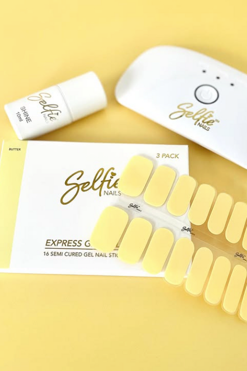 Yellow gel nail strips with packaging and a lamp on a yellow background