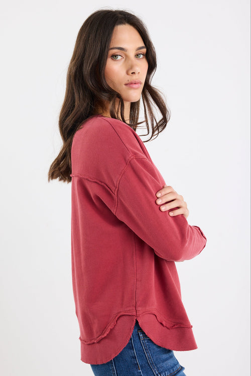 Woman wearing a red sweater and blue jeans on a white background