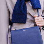 Person wearing a blue scarf and holding a blue handbag with a visible brand logo.