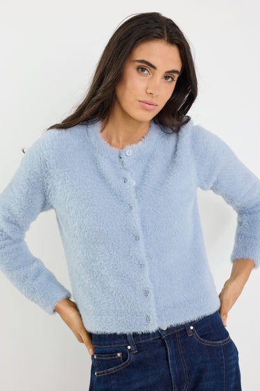 Woman wearing a light blue cardigan against a white background