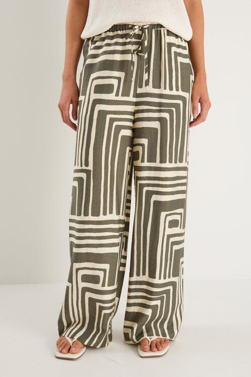 Woman wearing high-rise, wide-leg pants with an abstract khaki and ivory geo print and elasticated waistband with drawstring.