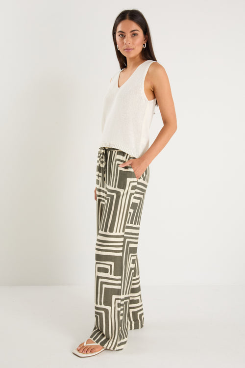 Woman wearing high-rise, wide-leg pants with an abstract khaki and ivory geo print and elasticated waistband with drawstring.