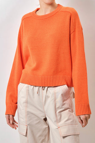 Model wears an orange knit 