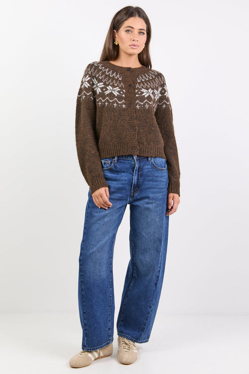 Woman wearing a brown patterned sweater and blue jeans on a white background