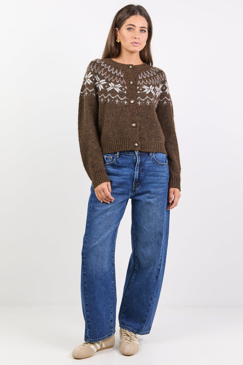 Woman wearing a brown patterned sweater and blue jeans on a white background