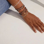 Hand wearing multiple bracelets on a light background