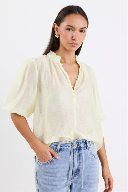 woman wearing yellow sheer blouse with blue jeans
