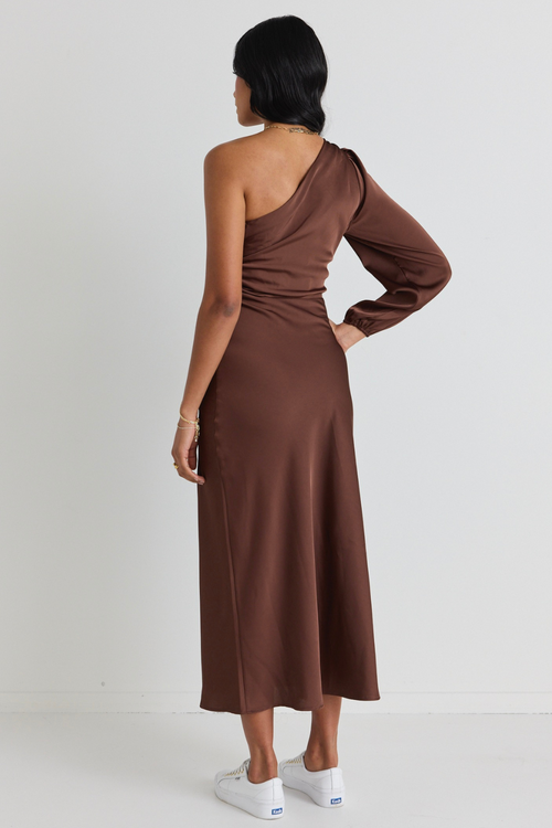 model wears a brown satin one shoulder dress with white sneakers