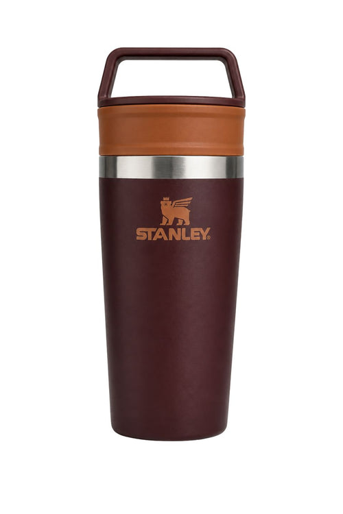 Stanley insulated travel tumbler with a dark burgundy body, a warm brown lid and carrying handle, and a silver stainless steel band around the middle.