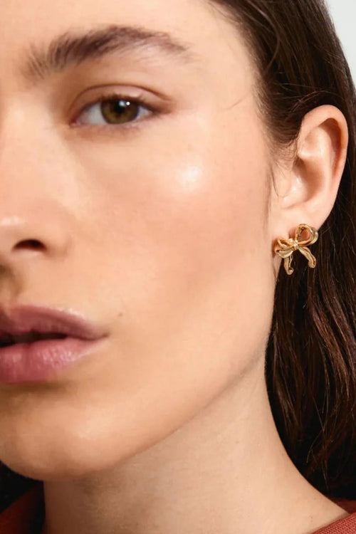 Close-up of a woman wearing gold earrings with a neutral background
