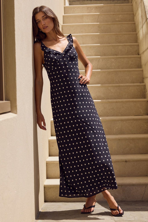 Woman in a black polka dot dress standing on a staircase