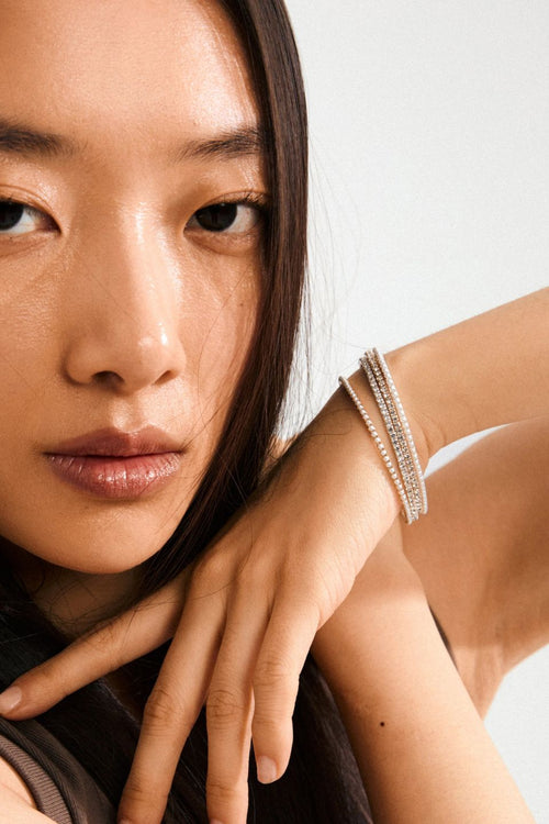 Close-up of a person wearing a bracelet on a plain background