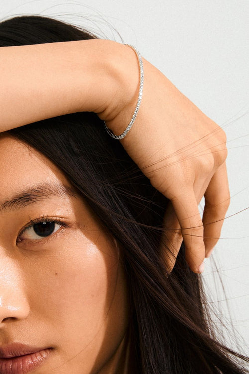 Close-up of a person with a silver bracelet on a plain background