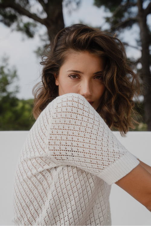 Woman wearing a short sleeve, open-knit ivory tee with a crew neck 