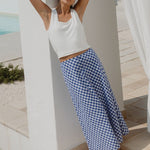 Woman wearing a blue gingham skirt and white tank in gorgeous villa