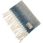 Gray and blue plaid blanket with white fringes on a white background