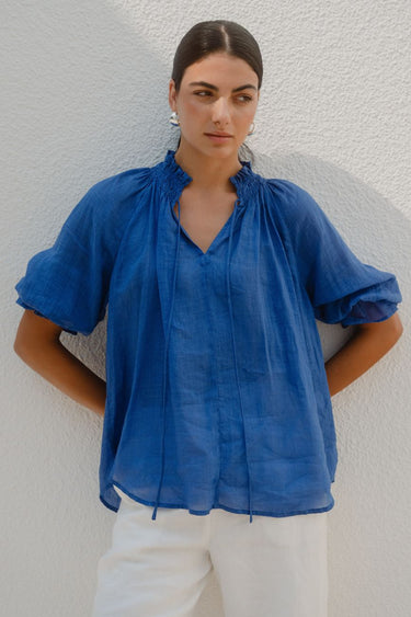 Woman wearing a blue top and white pants