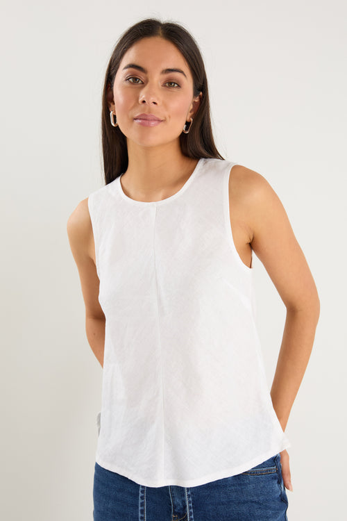 Model wears a white linen tank top with dark denim jeans