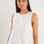 Model wears a white linen tank top with dark denim jeans