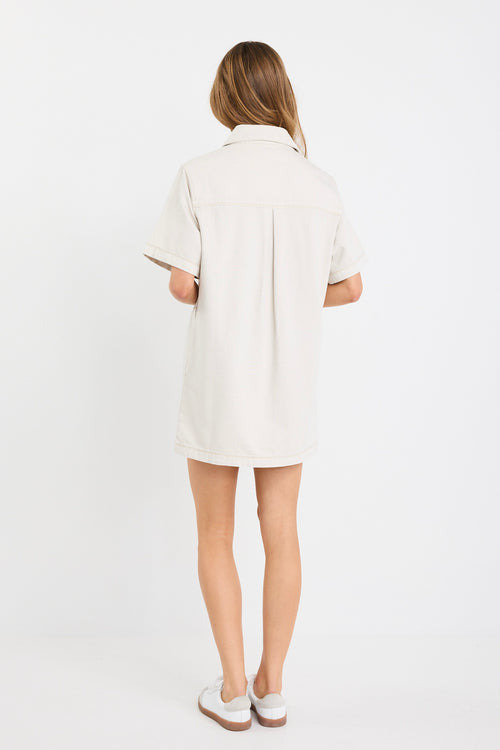 The model wears a ecru denim mini shirt dress with sneakers