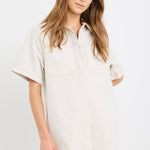 The model wears a ecru denim mini shirt dress with sneakers