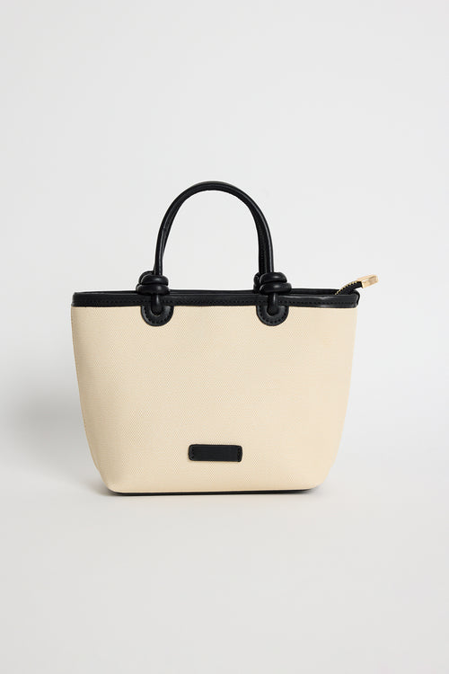 Natural canvas mini handbag with black PU trim, small knotted top handles and a long detachable shoulder strap, photographed against a plain background