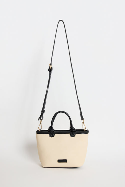 Natural canvas mini handbag with black PU trim, small knotted top handles and a long detachable shoulder strap, photographed against a plain background