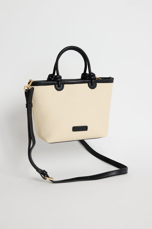 Natural canvas mini handbag with black PU trim, small knotted top handles and a long detachable shoulder strap, photographed against a plain background