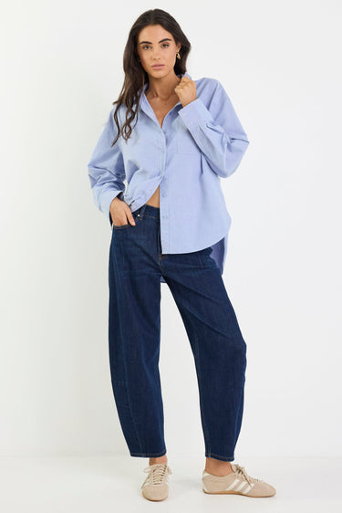 Woman wearing a light blue shirt and dark blue pants on a white background