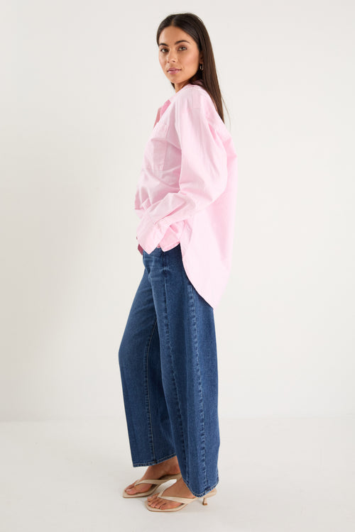 model wears a pink oversized shirt with blue jeans